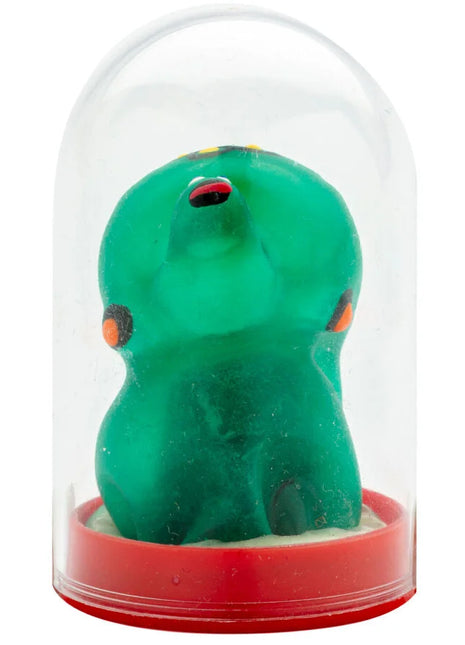 Eine transluzente grüne, handbemalte neuheitskondom-schildkröte mit orange und schwarz unter einer glaskuppel auf rotem sockel