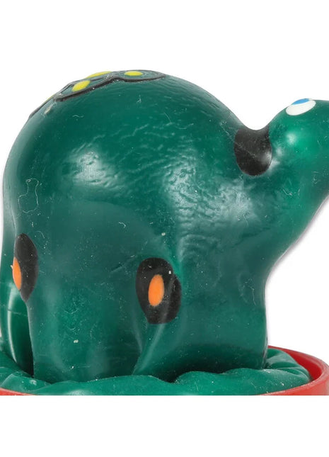 Grüner plastikspielzeug-oktopus mit schwarzen und orangen augenpunkten auf rotem rundem sockel in handbemalten neuheitskondomen schildkröte