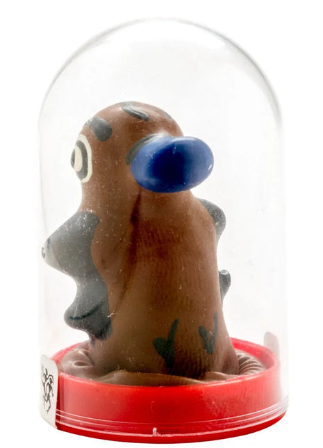 Braune tonfigur mit blauem ohr und grauen akzenten unter glaskuppel auf rotem kunststoffsockel in kondomerie kondomen