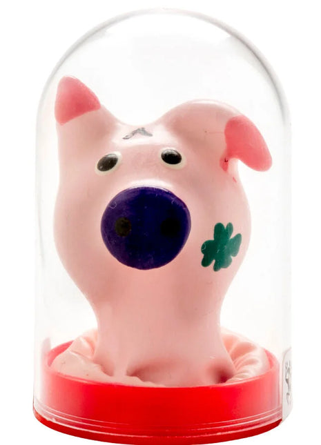 Pink keramische Schweinekopfformige Kondome mit blauer Nase und grünem Kleeblatt unter Glasglocke auf rotem Sockel