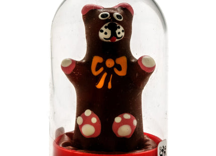 Handbemalte neuheitskondome teddybaer als schokoladenfigur mit rosa ohren, gepunkteten pfoten und gelber schleife unter glaskuppel auf rotem sockel