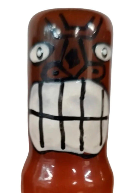 Glänzende braune keramikfigur mit weißem augen und kariertem mund im condomerie tiki totem friki 02 design