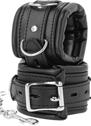 Schwarze gepolsterte bdsm-handschellen aus leder mit silbernen metallverschlüssen und d-ringen für bondage