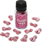 Eine klare plastflasche mit schwarzem deckel und pinkem etikett mit knochenmustern gefüllt mit roten zuckerbedeckten gummibärchen in form von penis mit erdbeer-kirsch-geschmack diablo picante candy sexy glas