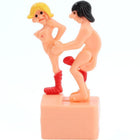 Pinkfarbene plastikfigur zweier nackerter figuren mit blondem und schwarzem haar eine mit roten stiefeln rückansicht