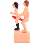 Pinkes plastikfigur diablo picante mit zwei nackten figuren eine trägt schwarze stiefel und roten string auf basis