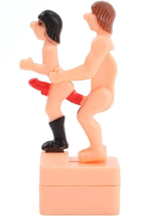Pinkes plastikfigur diablo picante mit zwei nackten figuren eine trägt schwarze stiefel und roten string auf basis