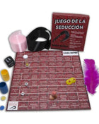 Rotes kama sutra spielbrett mit spanischem text und spielfeld umgeben von würfeln, bunten bechern, feder und schwarzem gürtel