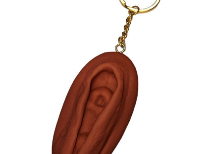 Brauner vagina-schlüsselanhänger diablo picante mit goldfarbenem metallring und kette in dunkler tonfarbe