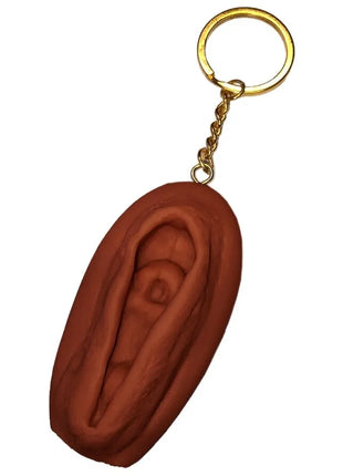 Brauner vagina-schlüsselanhänger diablo picante mit goldfarbenem metallring und kette in dunkler tonfarbe