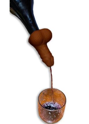 Braune silikon weinkaraffe in penisform mit dunklem flaschenhals gießt roten wein ins glas diablo picante
