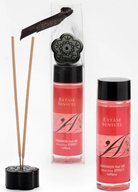 Schwarze floral geformte diffuser basis mit holzstäbchen und zwei rosa etikettierten extase sensuel massageolflaschen 100 ml