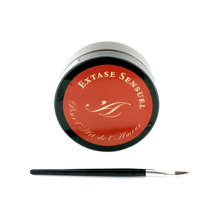 Ein eleganter schwarzer zylinderbehälter mit rotem deckel und goldener monogrammierung für extase sensual schokoladenkörperlack 50 ml