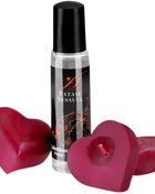 Ein klarer glas-rollerball mit schwarzem deckel und label extase sensuel neben zwei herzförmigen roten kerzen