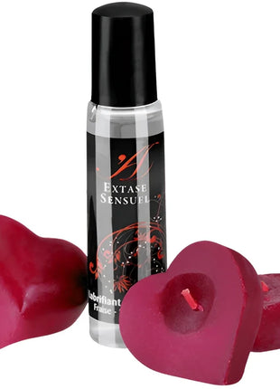 Ein klarer glas-rollerball mit schwarzem deckel und label extase sensuel neben zwei herzförmigen roten kerzen