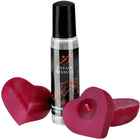 Ein klarer glas-rollerball mit schwarzem deckel und label extase sensuel neben zwei herzförmigen roten kerzen