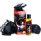 Eine klare glasflasche mit schwarzem deckel gefüllt mit bernsteinfarbenem massageöl lart de lamour für das extase sensual fantasy set für zwei