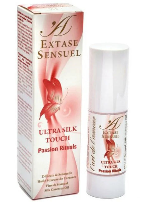 Eine elegante weiße zylinderflasche mit extase sensual ultra silk touch massageöl passion rituals seidenöl aus carnaubawachs neben rosa- und cremeverpackung mit rotem schmetterling