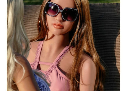 Eine frau mit langen braunen haaren trägt ein pinkes oberteil und große dunkle sonnengläser mit glitzersteinen bei pipedream extreme toys fantasy dolls carmen puppe 165 cm