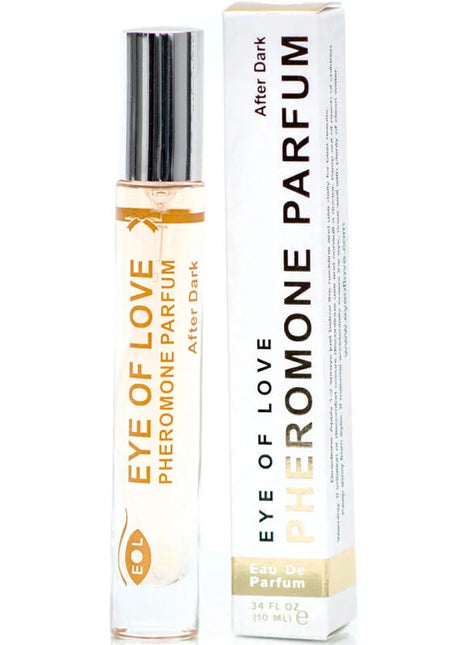 A sleek transparent glass rollerball bottle with silver cap and gold eye of love pheromon parfum after dark label beside white box