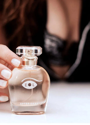 Eine klare glas-parfümflasche eye of love eol phr parfum deluxe 50 ml mit facettiertem silberdeckel und bernsteinfarbener flüssigkeit