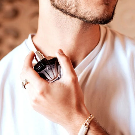 Ein schlanker dunkelvioletter diamantförmiger parfumflakon mit silberner kappe und der eingravierung magnificent für him 30 ml