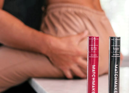 Zwei zylindrische eye of love matchmaker mascara tubes in rot und schwarz mit weißer schrift auf matter oberfläche