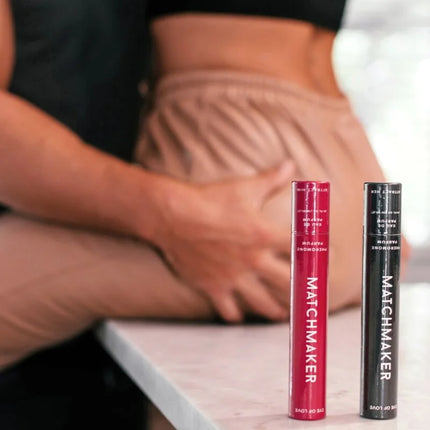 Zwei zylindrische eye of love matchmaker mascara tubes in rot und schwarz mit weißer schrift auf matter oberfläche
