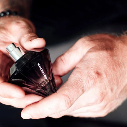 Ein dunkel gefacettetes glas-parfümfläschchen eye of love matchmaker black diamond pheromon-parfüm mit silbernen spraykopf 30 ml