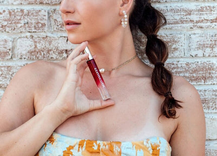 Ein glänzendes, durchsichtiges rotes lipgloss in einem schlanken röhrchen mit silberkappe von manchurer im 10 ml eye of love matchmaker red diamond parfum set