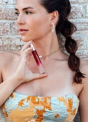 Ein glänzendes, durchsichtiges rotes lipgloss in einem schlanken röhrchen mit silberkappe von manchurer im 10 ml eye of love matchmaker red diamond parfum set