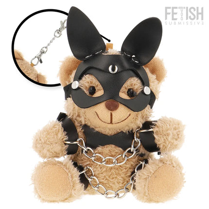 Ein tanfarbener plüsch-teddybär fetisch submissive mit schwarzer ledermaske, nieten, ohrstücken, schwarzem harness und silberner kette