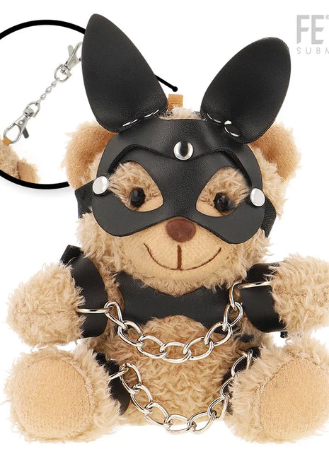 Ein tanfarbener plüsch-teddybär fetisch submissive mit schwarzer ledermaske, nieten, ohrstücken, schwarzem harness und silberner kette