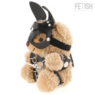 Ein plüschiger tanfarbener teddy bär im fetisch submissive stil mit schwarzer ledermaske, silbernen nieten und kettenharness