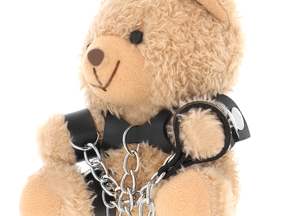 Ein plüschiger tanfarbener yohgi teddybär mit schwarzem ledergeschirr und silbernen kettensperren im bdsm stil