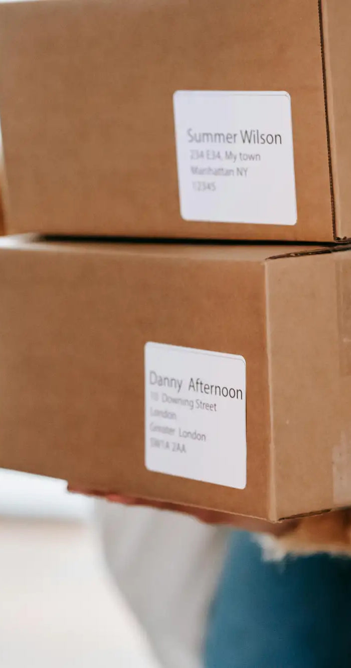 Zwei gestapelte braune Pappkartons mit weißen Versandetiketten.