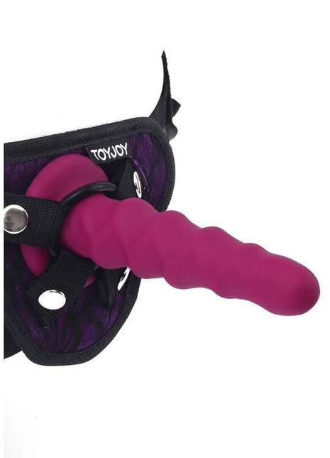 Ein lebhafter magentafarbener silikon dildo mit strukturierter oberfläche und gebogenem design im toyjoy harness