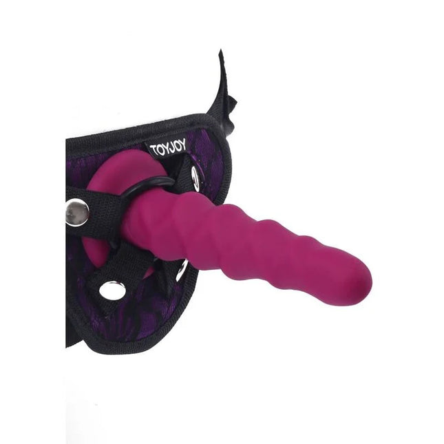 Ein lebhafter magentafarbener silikon dildo mit strukturierter oberfläche und gebogenem design im toyjoy harness