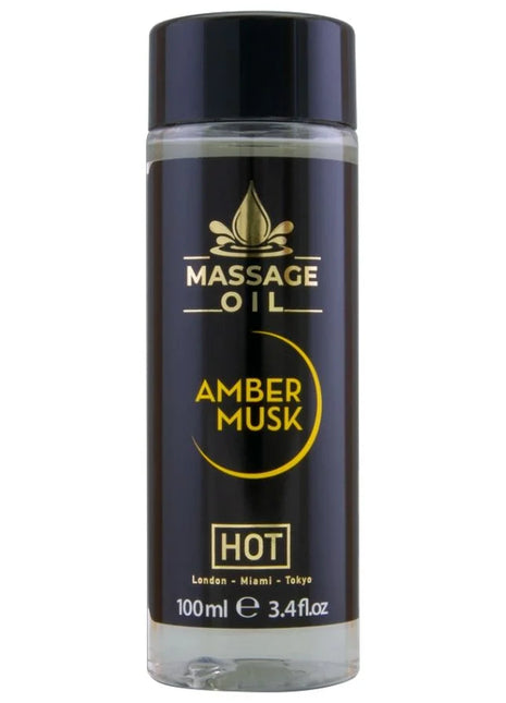 Schwarze glasflasche mit schwarzem deckel und goldener aufschrift massageöl amber musk hot im 100 ml format