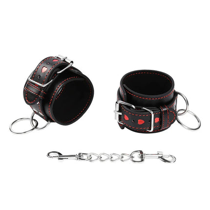 Ohmama fetish handschellen aus schwarzem leder mit roten nähten herzförmigen aussparungen und silberner kette