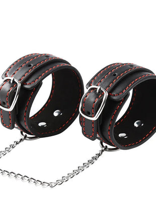 Schwarze leder handgelenkfesseln mit roter nähung und silbernen metallverschlüssen verbunden durch eine kettenschlaufe