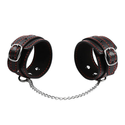 Schwarze leder handgelenkfesseln mit roten nähten und silbernen schnallen verbunden durch herzförmige kette von ohmama fetish