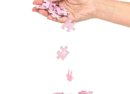 Eine hand hält und lässt rosa puzzle teile aus dem sekret play puzzelspiel sexxxzzle fallen