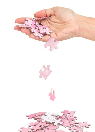 Eine hand hält und lässt rosa puzzle teile aus dem sekret play puzzelspiel sexxxzzle fallen