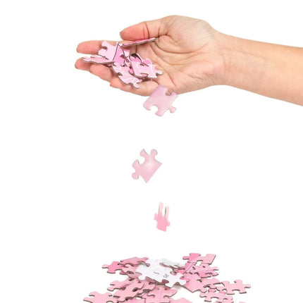 Eine hand hält und lässt rosa puzzle teile aus dem sekret play puzzelspiel sexxxzzle fallen