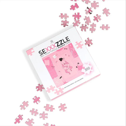 Rosa puzzlebox mit sexxxzzle branding und verstreuten pinken puzzleteilen für das secret play puzzlespiel sexxxzzle