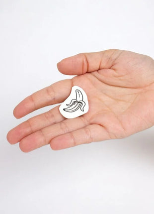 Weißer email-pin in bananenform mit schwarzer linienzeichnung aus der candy collection temporärer tattoos set