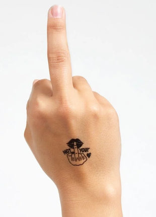 Schwarzes temporärtattoo mit stylisierter hand und lips sowie text not your babe auf der handgelenkrückseite aus der spicy collection