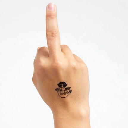 Schwarzes temporärtattoo mit stylisierter hand und lips sowie text not your babe auf der handgelenkrückseite aus der spicy collection