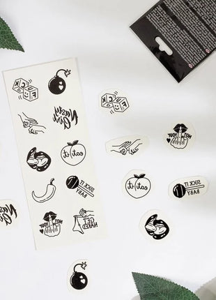 Ein set mit 10 schwarz-weißen temporären tattoos aus der spicy kollektion mit verspielten designs wie würfeln und bombs